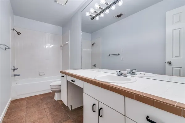 a bathroom with a granite countertop sink a toilet a mirror a bathtub and shower