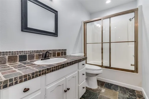 a bathroom with a granite countertop sink a toilet and a mirror