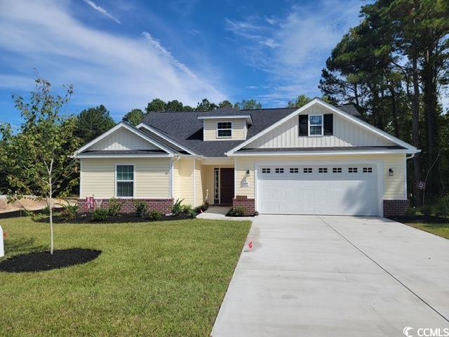 Craftsman-style home featuring brick siding, driveway, a front yard, and board and batten siding