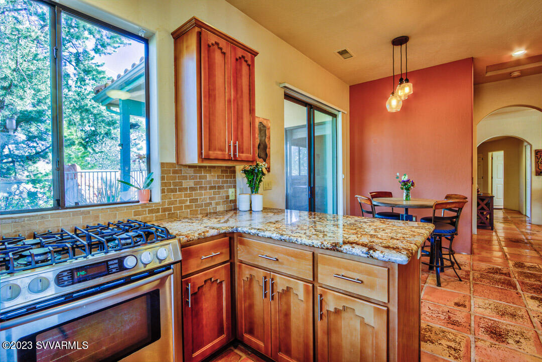 55 Roundup Road Sedona, AZ 86336 - Photo 14 of 35 a kitchen with stainless steel appliances granite countertop a stove a sink dishwasher and a dining table with wooden cabinet
