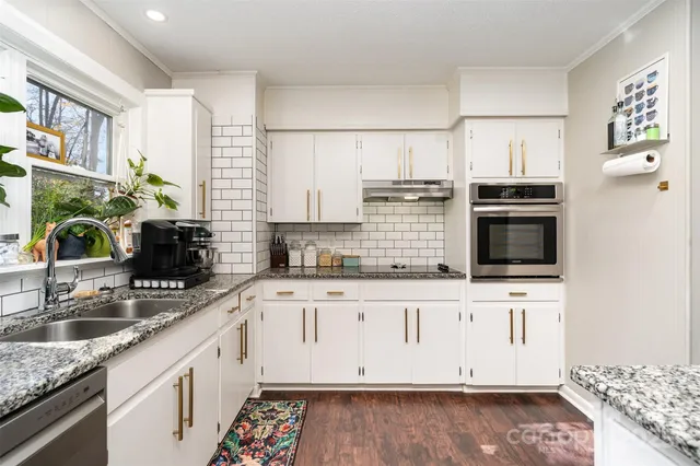 a kitchen with granite countertop a sink stove and cabinets