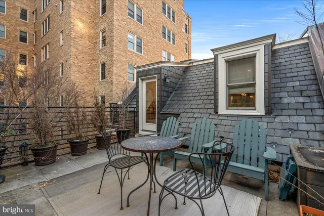a view of a brick house with a chairs and table in a patio