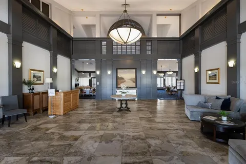 a view of a dining room and livingroom with furniture wooden floor a rug a fireplace and a chandelier