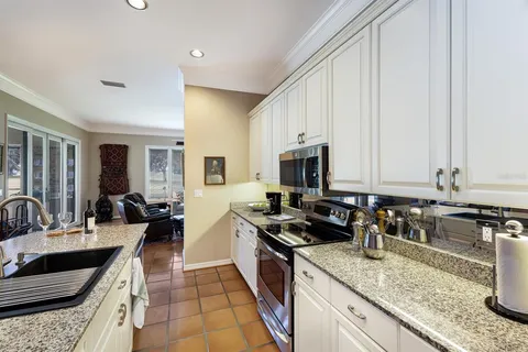 a kitchen with granite countertop stainless steel appliances a sink a counter top space and cabinets