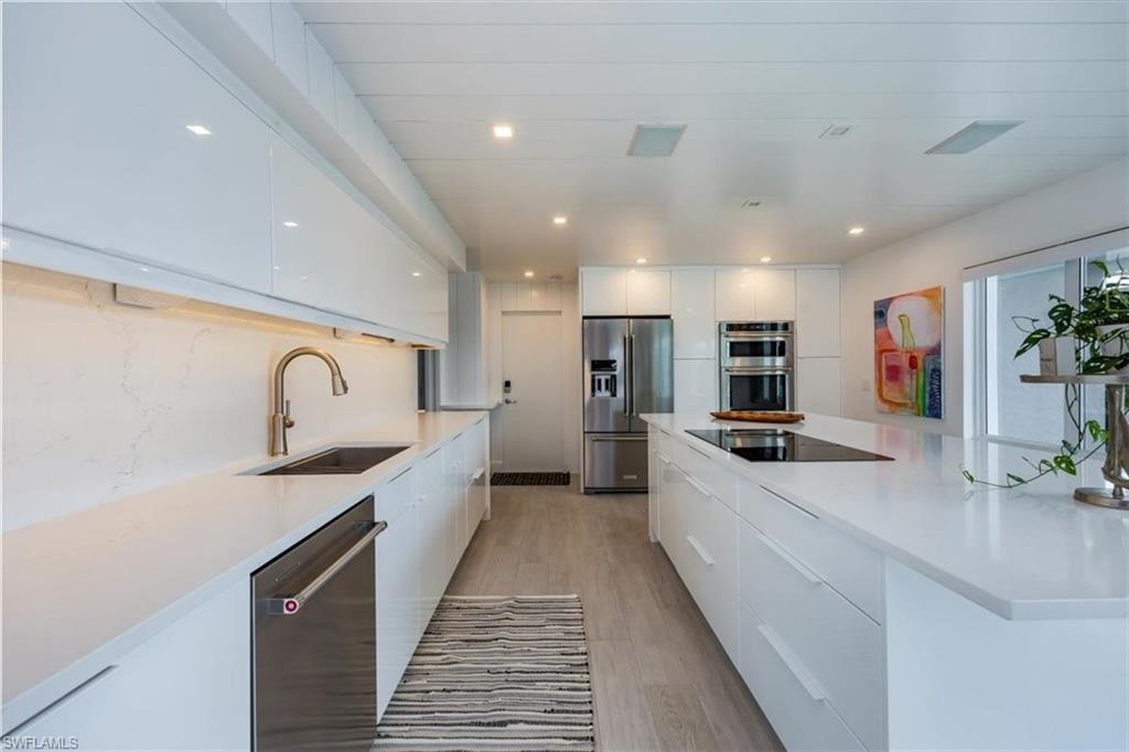 1100 8th Avenue South, Unit 123F Naples, FL 34102 - Photo 11 of 30 a large kitchen with stainless steel appliances granite countertop a sink and cabinets
