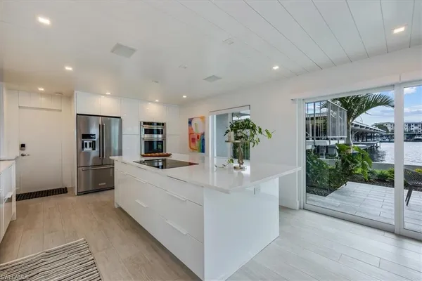 a large white kitchen with large windows and refrigerator