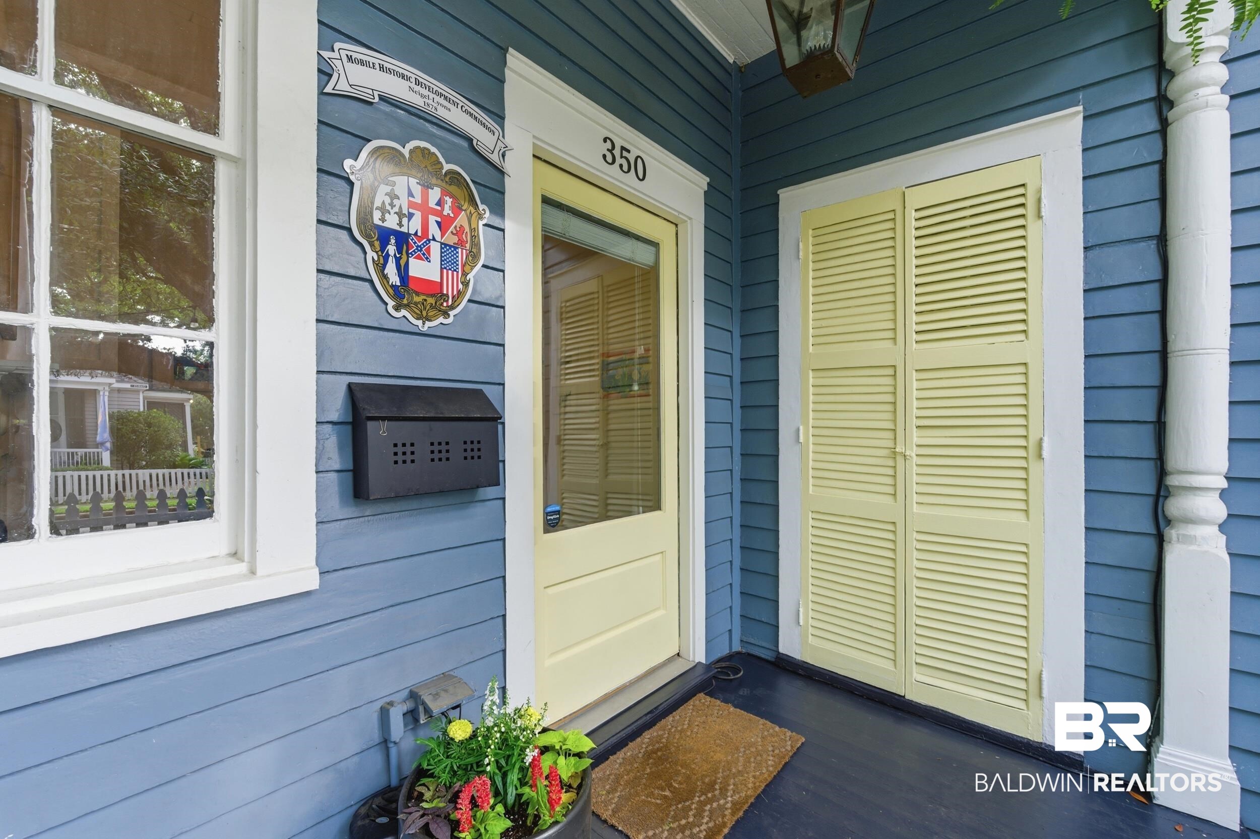 350 Charles Street Mobile, AL 36604 - Photo 40 of 52 Exterior featuring horizontal siding, a light-colored main entry door with glass paneling, and an adjacent set of louvered shutters