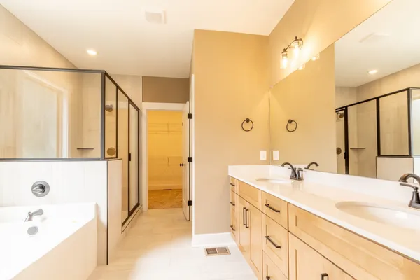 a spacious bathroom with a tub sink shower and mirror