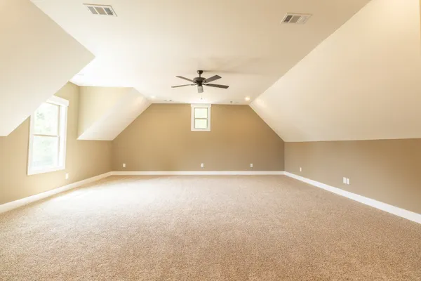 an empty room with windows and a ceiling fan