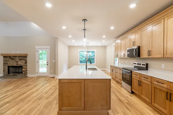 a kitchen with kitchen island granite countertop a stove a sink a refrigerator dining table and chairs with wooden floor