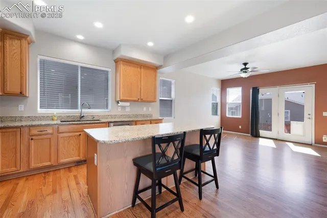 a kitchen with stainless steel appliances granite countertop wooden floor a dining table and chairs