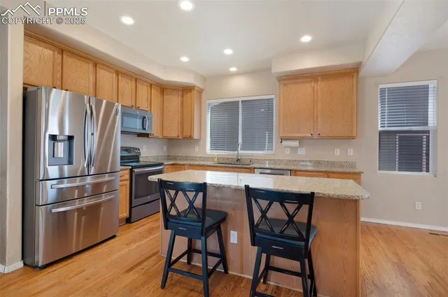 a kitchen with a refrigerator a stove a sink and a dining table with wooden floor