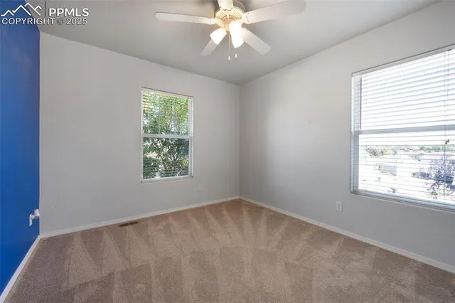 a view of an empty room with window and chandelier fan