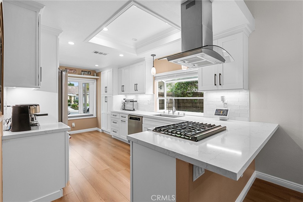 27251 Blakely Place Valencia, CA 91354 - Photo 8 of 31 a kitchen with stainless steel appliances a white stove top oven a sink dishwasher and white cabinets with wooden floor