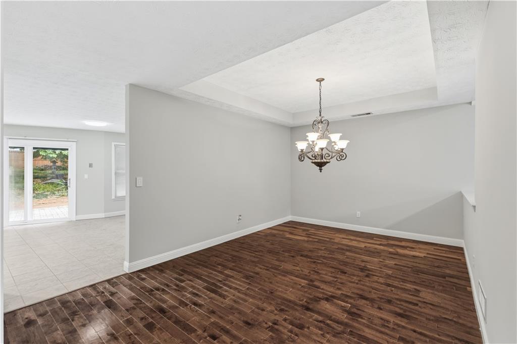2824 Carriage Rowe Duluth, GA 30096 - Photo 10 of 45 an empty room with wooden floor chandelier and windows