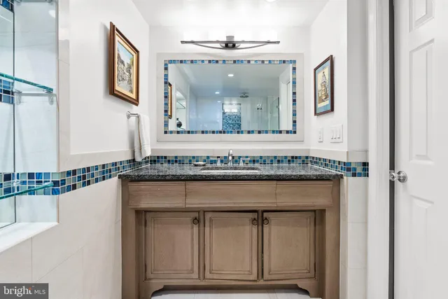 a view of a hallway with granite countertop a sink and a mirror