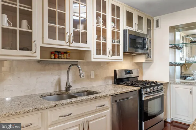 a kitchen with stainless steel appliances granite countertop white cabinets and window
