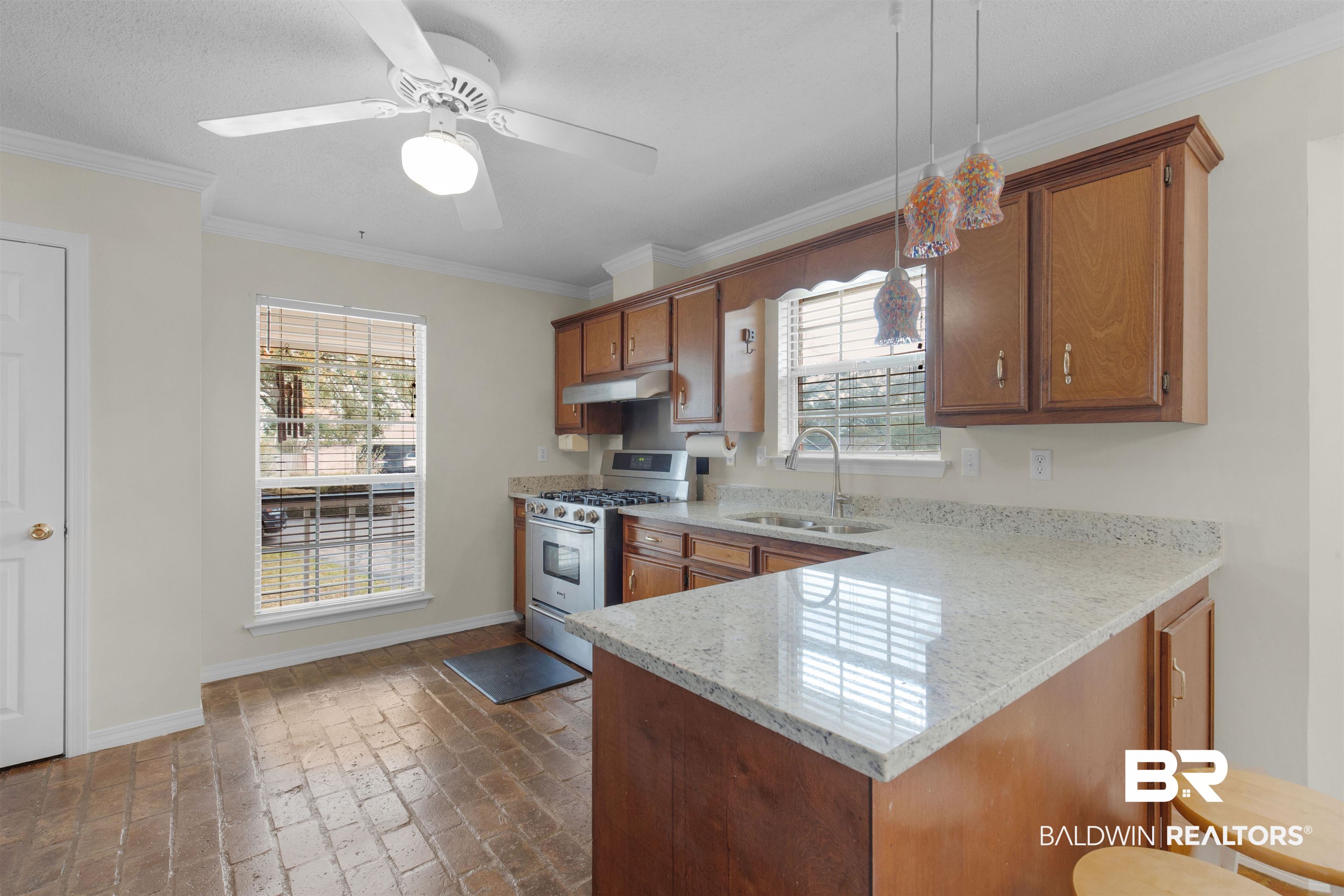 7225 Smithfield Road East Mobile, AL 36695 - Photo 6 of 27 Kitchen featuring stainless steel range with gas cooktop, under cabinet range hood, brown cabinets, brick floor, and a sink