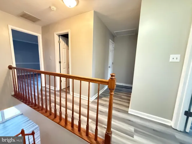 a view of a hallway with wooden floor and staircase