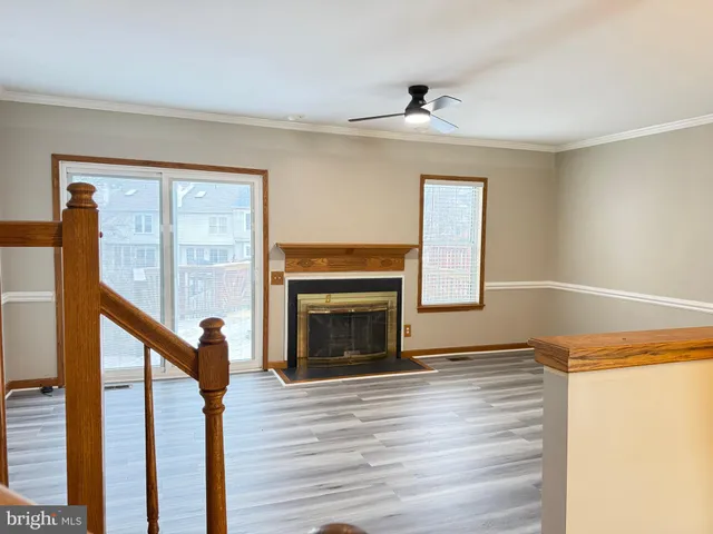 a view of an empty room with wooden floor fireplace and a window