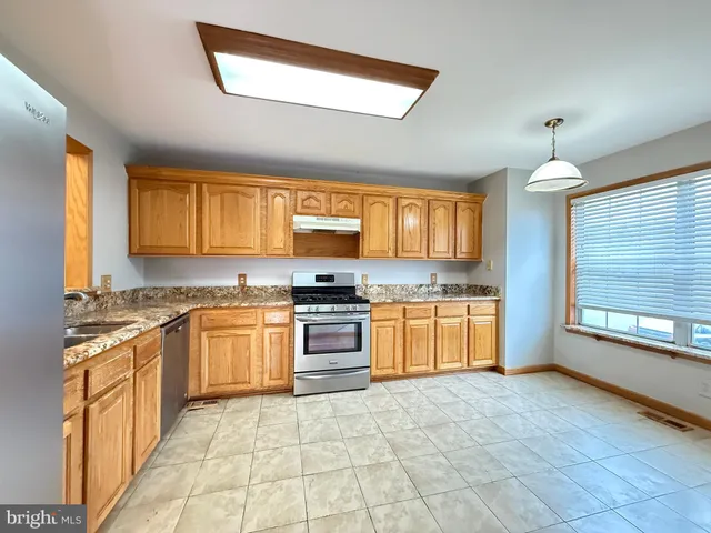 a large kitchen with stainless steel appliances granite countertop a stove sink and cabinets