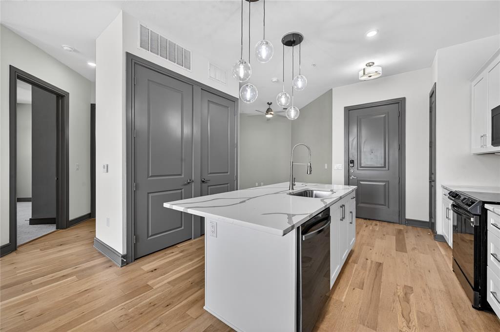 2700 Old Denton Road, Unit 2259 Carrollton, TX 75007 - Photo 8 of 39 a kitchen with kitchen island stainless steel appliances a chimney cabinets and wooden floor