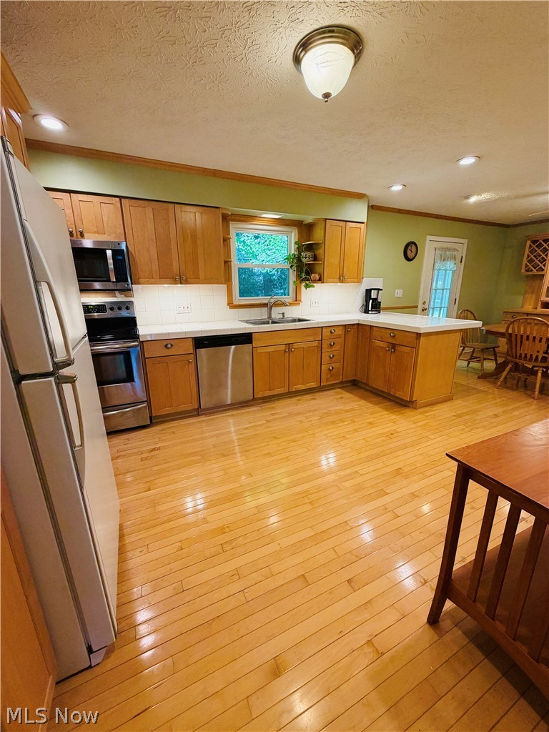 5770 Chapel Road Madison, OH 44057 - Photo 8 of 42 U-shaped kitchen with wood-finish flooring, light wood cabinetry, white countertops, and stainless steel appliances