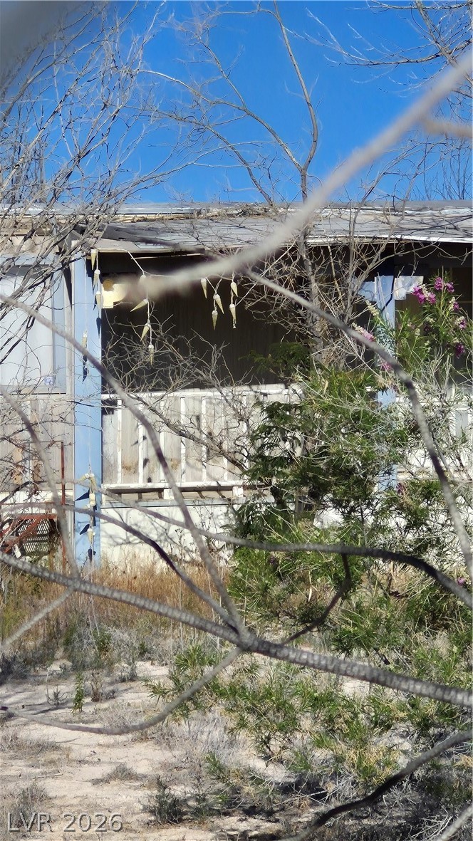 A partially obscured residential structure sits amidst dry brush and natural desert landscaping.