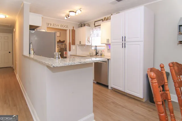 a kitchen with stainless steel appliances granite countertop a refrigerator a sink and white cabinets