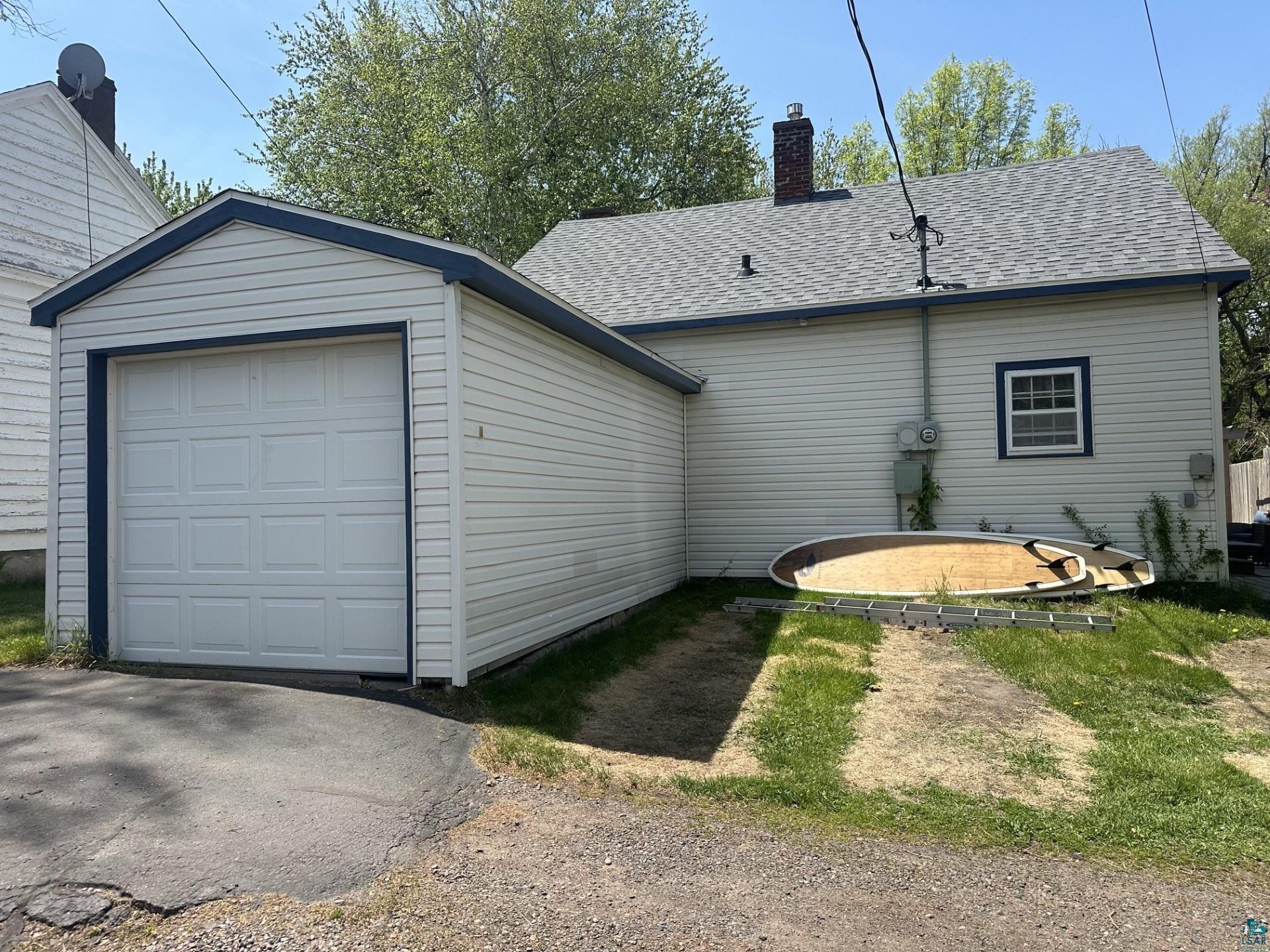 208 Chestnut Street Cloquet, MN 55720 - Photo 4 of 24 Detached garage with white panel door, light-colored siding, and dark trim