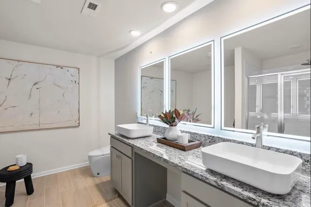 a bathroom with double vanity sinks a mirror and a toilet