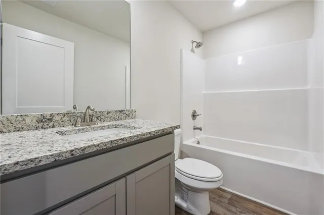 a bathroom with a granite countertop toilet sink and mirror