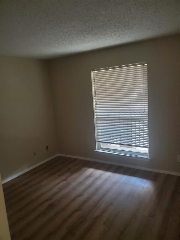 5532 Boca Raton Boulevard, Unit 290 Fort Worth, TX 76112 - Photo 13 of 16 Room featuring wood-finish flooring, a single window with zebra shades, and light-toned walls