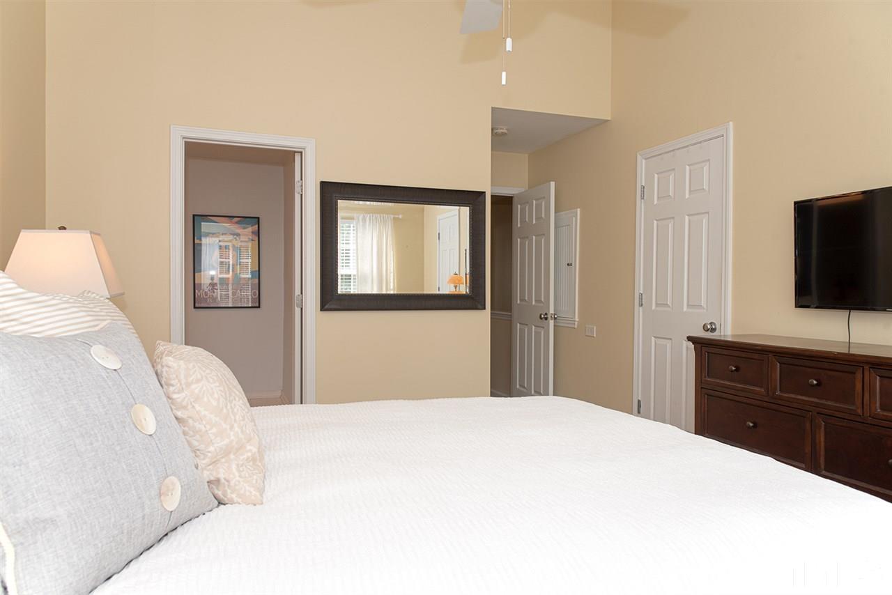 8272 City Loft Court Raleigh, NC 27613 - Photo 17 of 26 a bedroom with a large bed and a flat tv screen on dresser