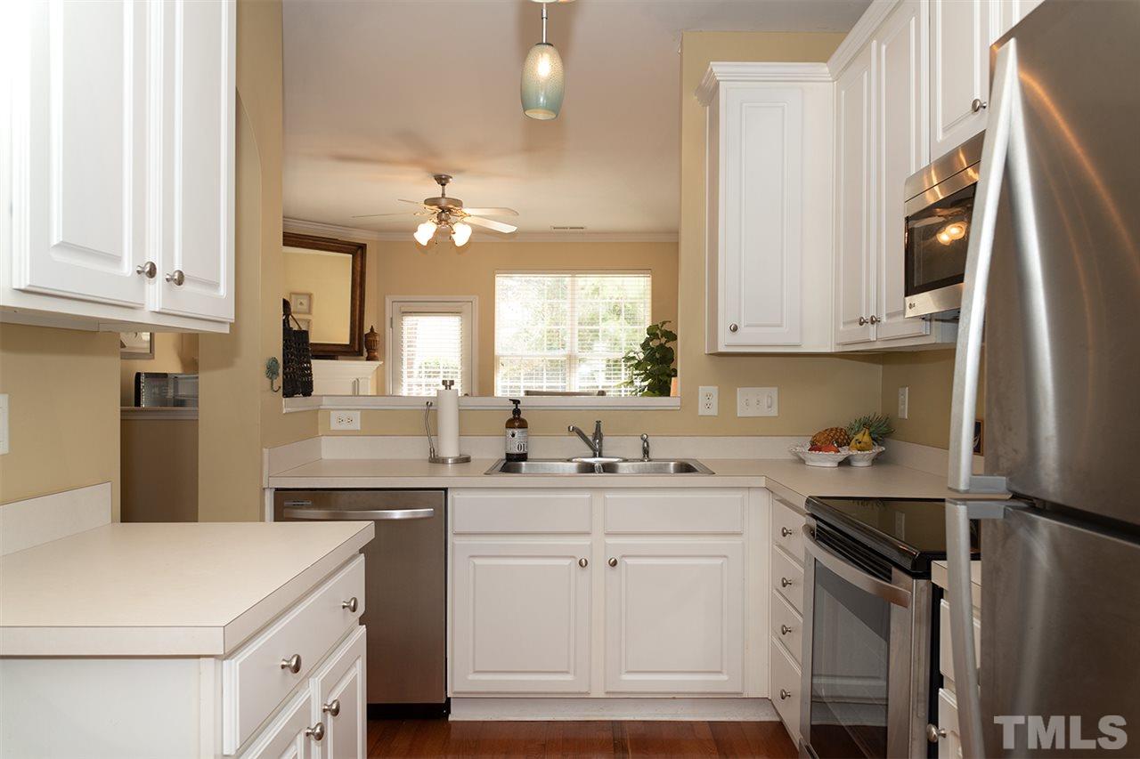 8272 City Loft Court Raleigh, NC 27613 - Photo 7 of 26 a kitchen with a sink dishwasher a refrigerator a stove and white cabinets with wooden floor