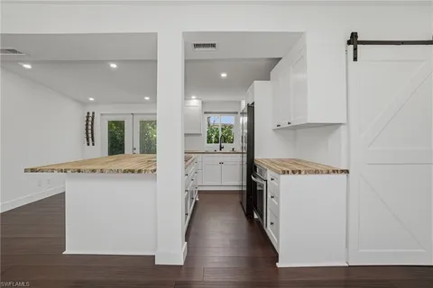 a large white kitchen with lots of counter space wooden floor and appliances