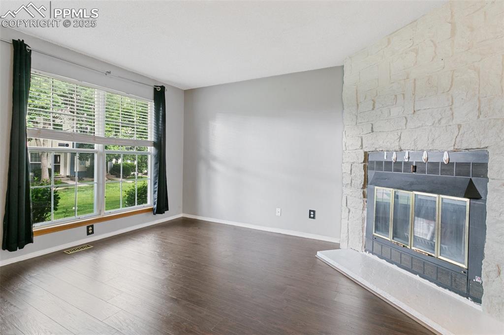 3457 Queen Anne Way Colorado Springs, CO 80917 - Photo 3 of 25 Unfurnished living room featuring wood finished floors and a stone fireplace
