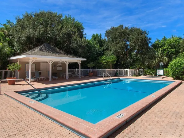 a view of a pool with a table and chairs under an umbrella