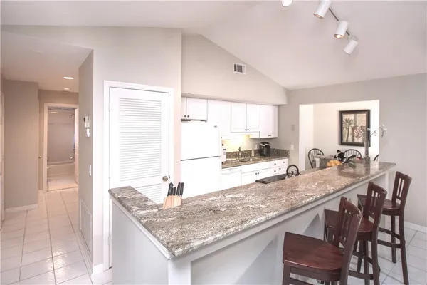 a kitchen with granite countertop kitchen island a table and chairs in it