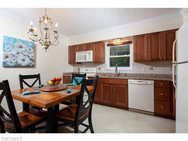 940 3rd Street South, Unit 104 Naples, FL 34102 - Photo 5 of 8 a kitchen with a dining table chairs and white cabinets