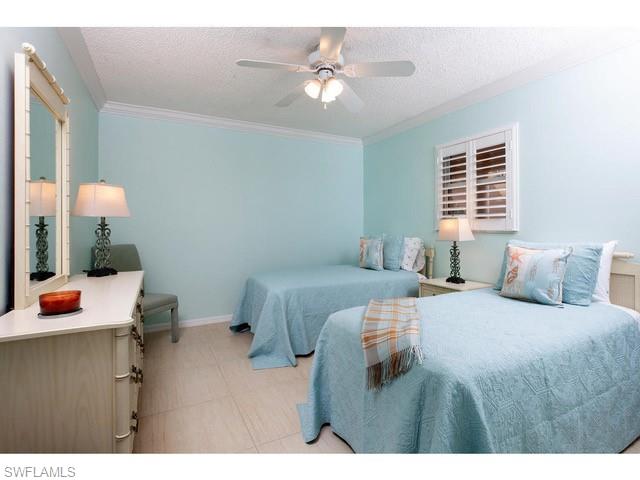 940 3rd Street South, Unit 104 Naples, FL 34102 - Photo 6 of 8 a bedroom with a bed and a chandelier