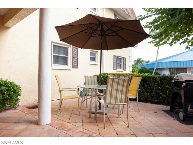 940 3rd Street South, Unit 104 Naples, FL 34102 - Photo 8 of 8 a patio table and chairs under an umbrella