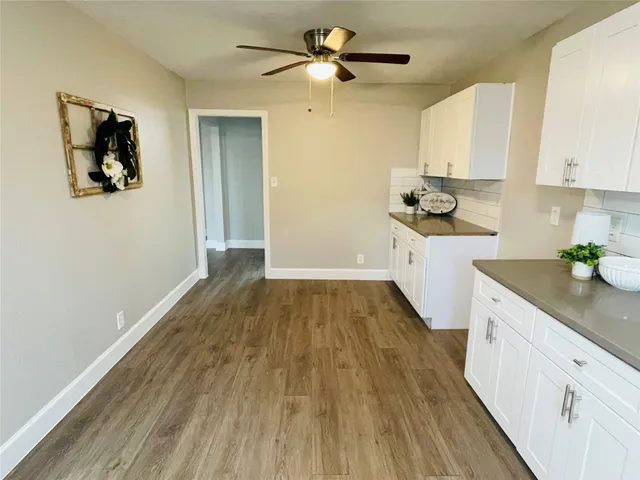 a kitchen with wooden floors and white cabinets