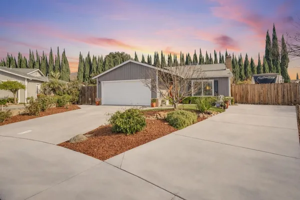 a front view of a house with a yard and trees