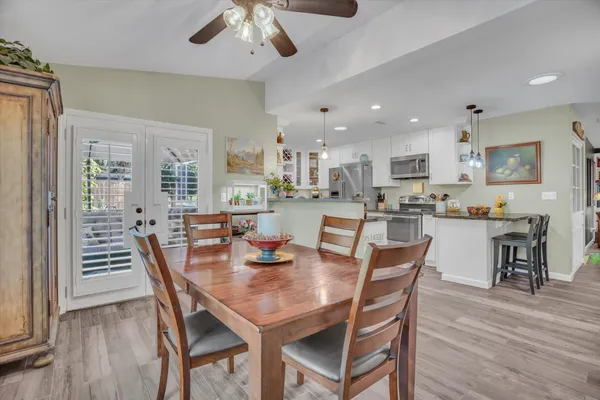 a dining room with stainless steel appliances a dining table chairs and wooden floor