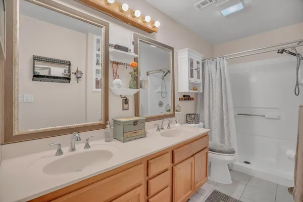 a bathroom with a double vanity sink toilet mirror and shower