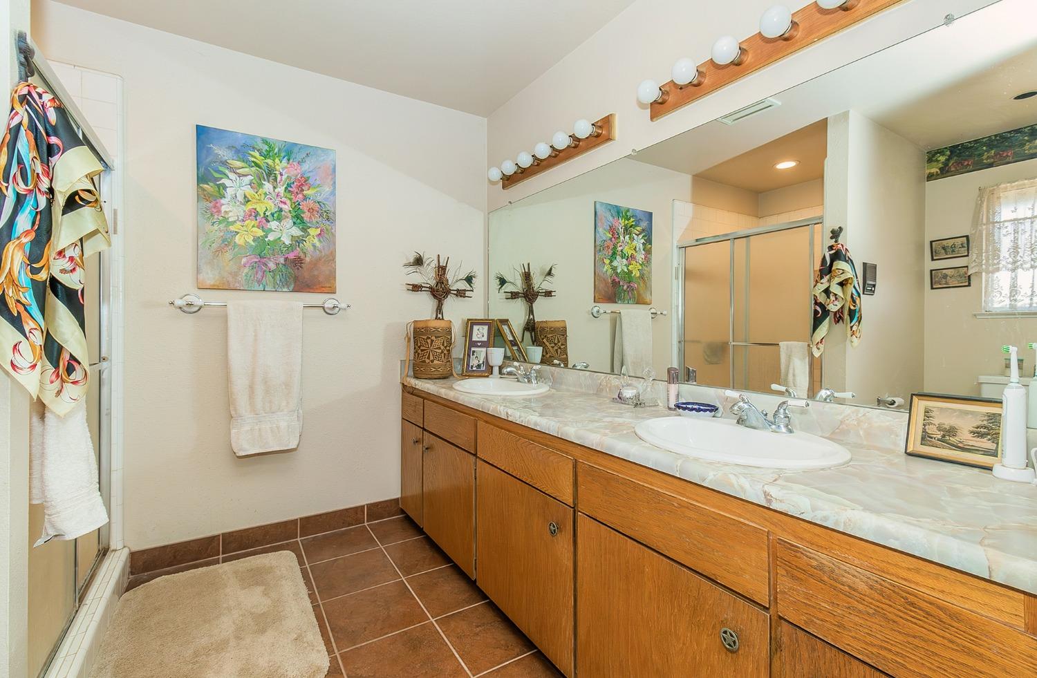 13016 Violet Lane Clovis, CA 93619 - Photo 17 of 41 a bathroom with a granite countertop sink a mirror a vanity and shower