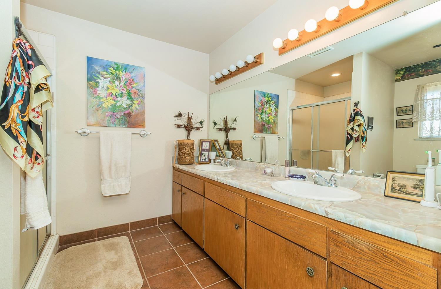 13016 Violet Lane Clovis, CA 93619 - Photo 18 of 41 a bathroom with a granite countertop sink a mirror a vanity and shower