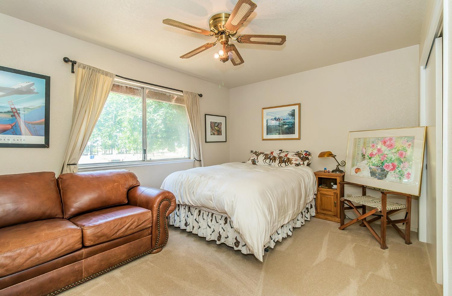 13016 Violet Lane Clovis, CA 93619 - Photo 20 of 41 a spacious bedroom with a bed a couch and a window
