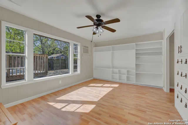 a view of an empty room with a window and wooden floor